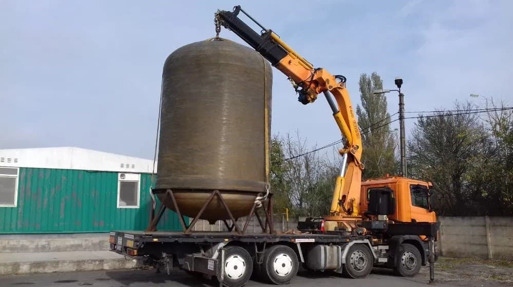 Macara montata pe camion ridicand un rezervor metalic