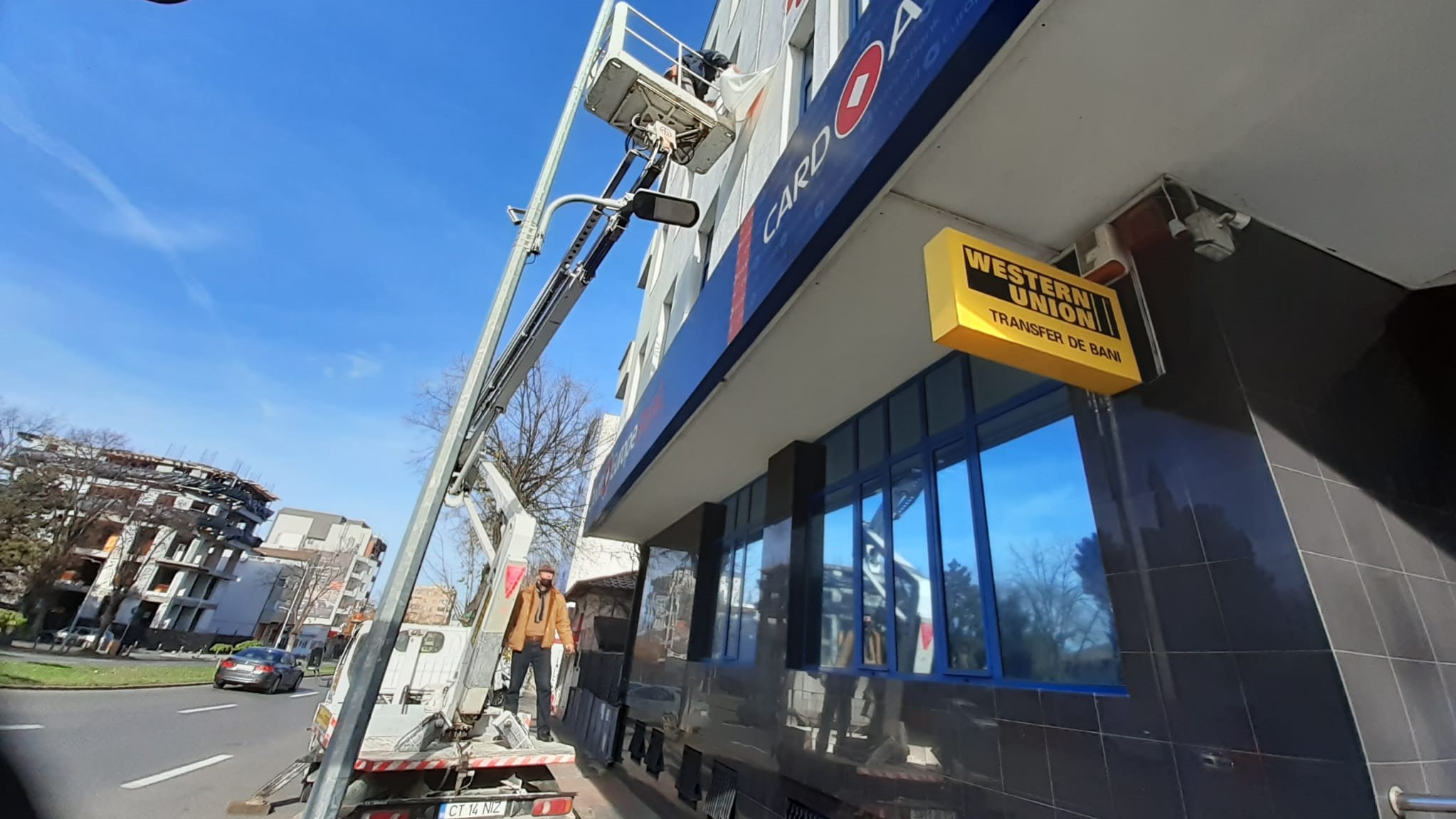 a person in a white truck mounted boom lift removing banner of an apartment building