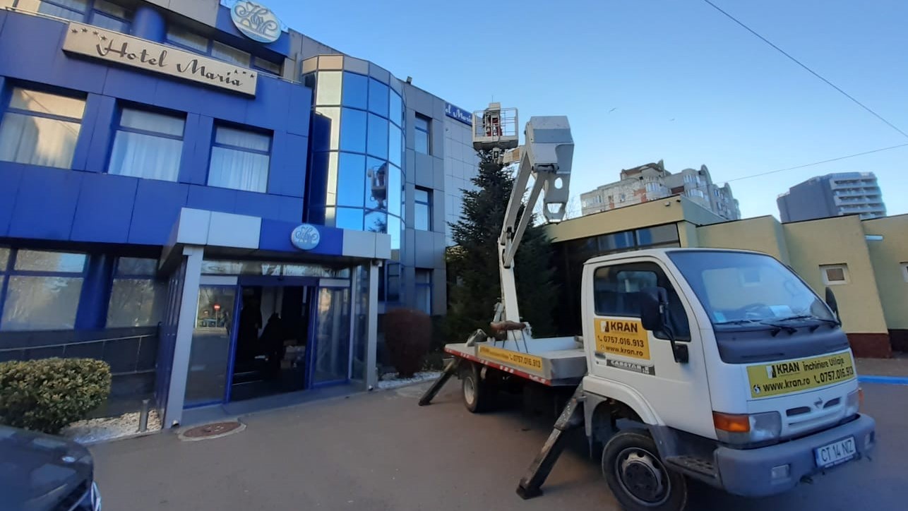 white truck mounted boom lift near hotel maria