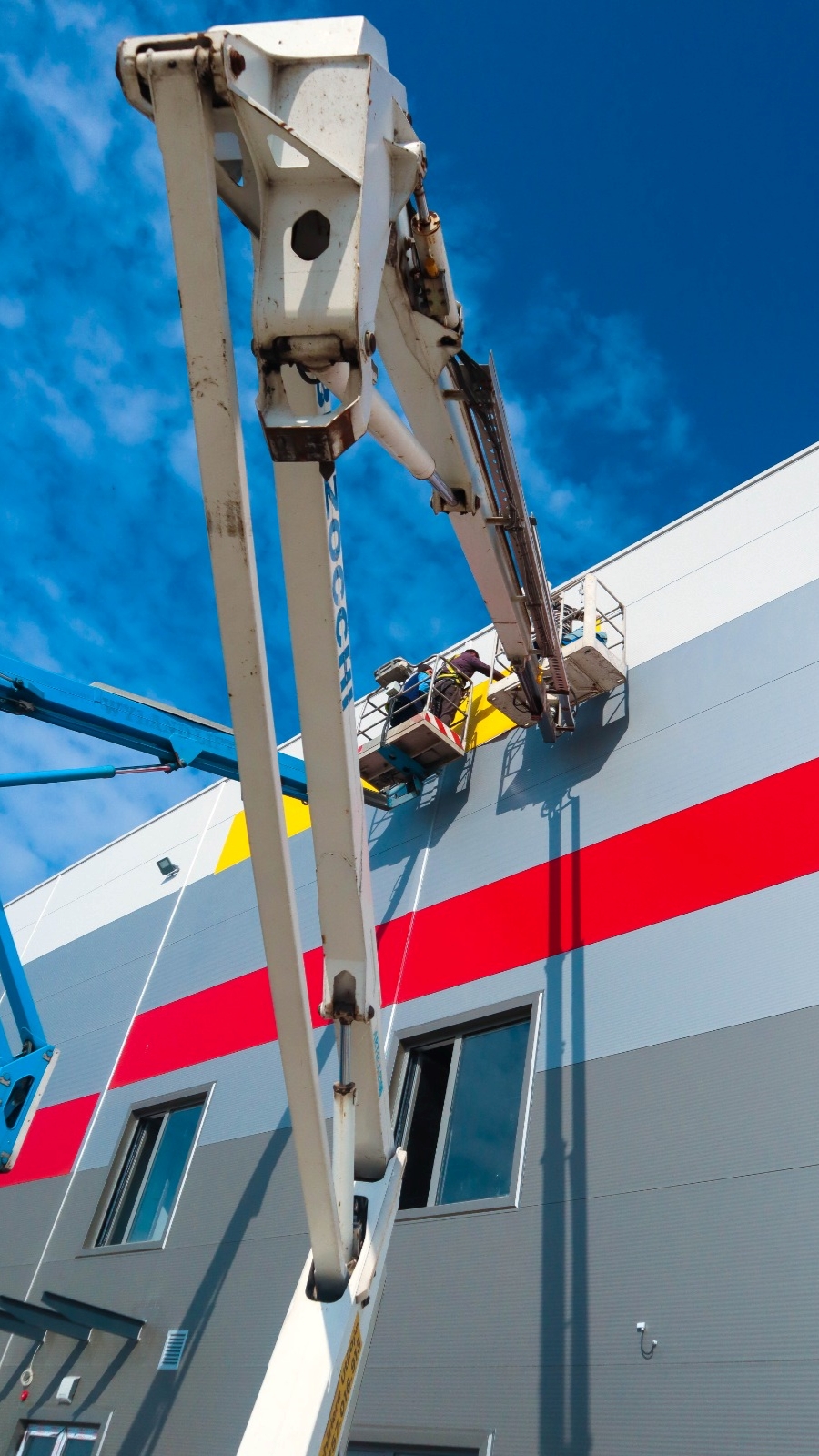 Sticking the Logo Wall Stickers with the use of two truck-mounted boom lifts